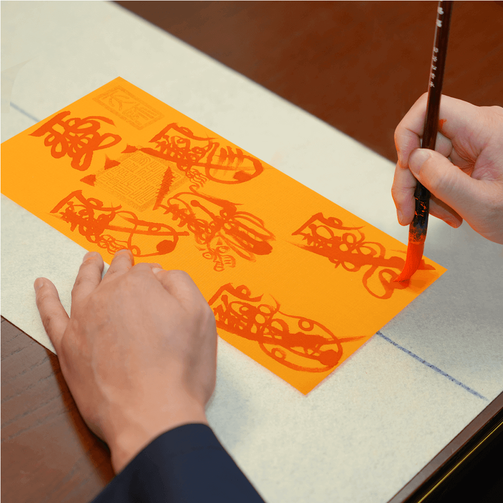 Master calligrapher hand-painting the intricate Five Wealth Gods Talisman design with brush