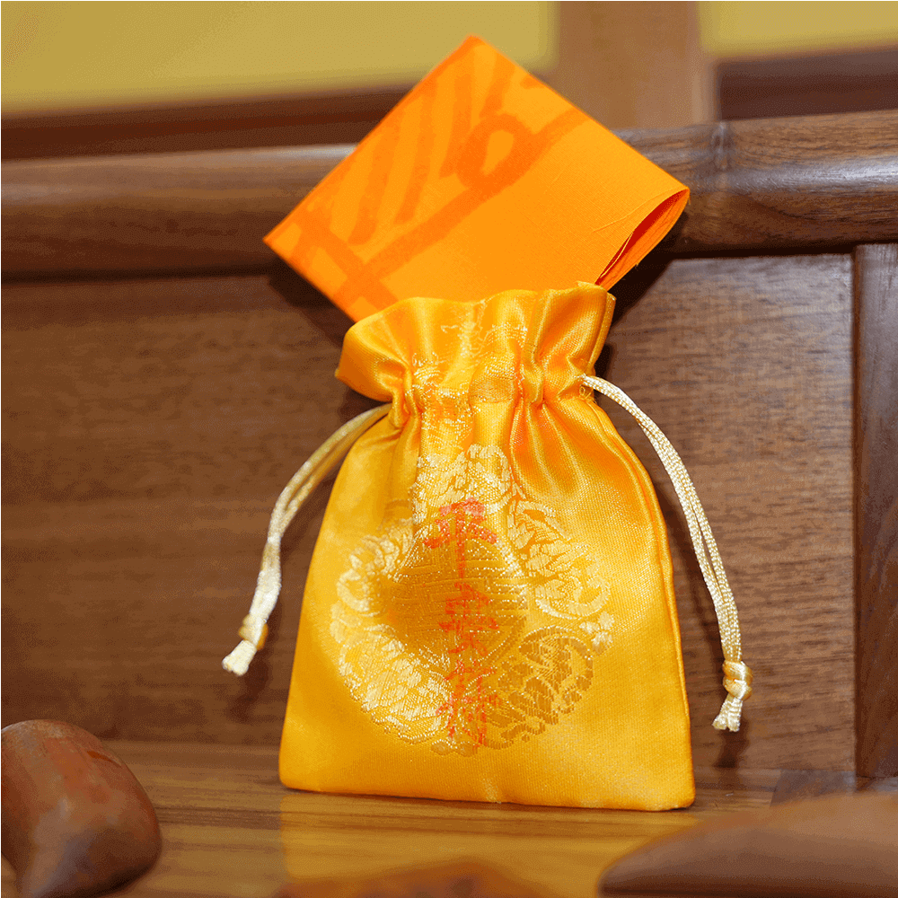 Safety Talisman charm displayed upright leaning against a plain wall background.