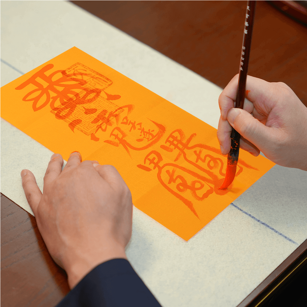 Master inscribing Taisui Talisman with sacred symbols, channeling protective forces against astrological conflicts.
