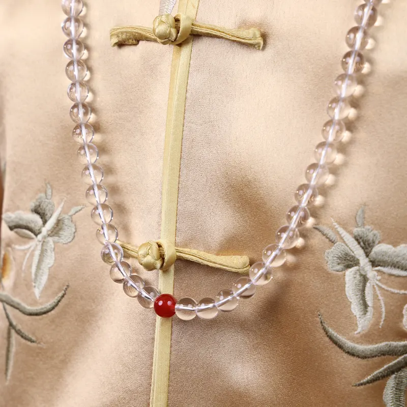 Close up of a clear quartz bead necklace worn on the chest.
