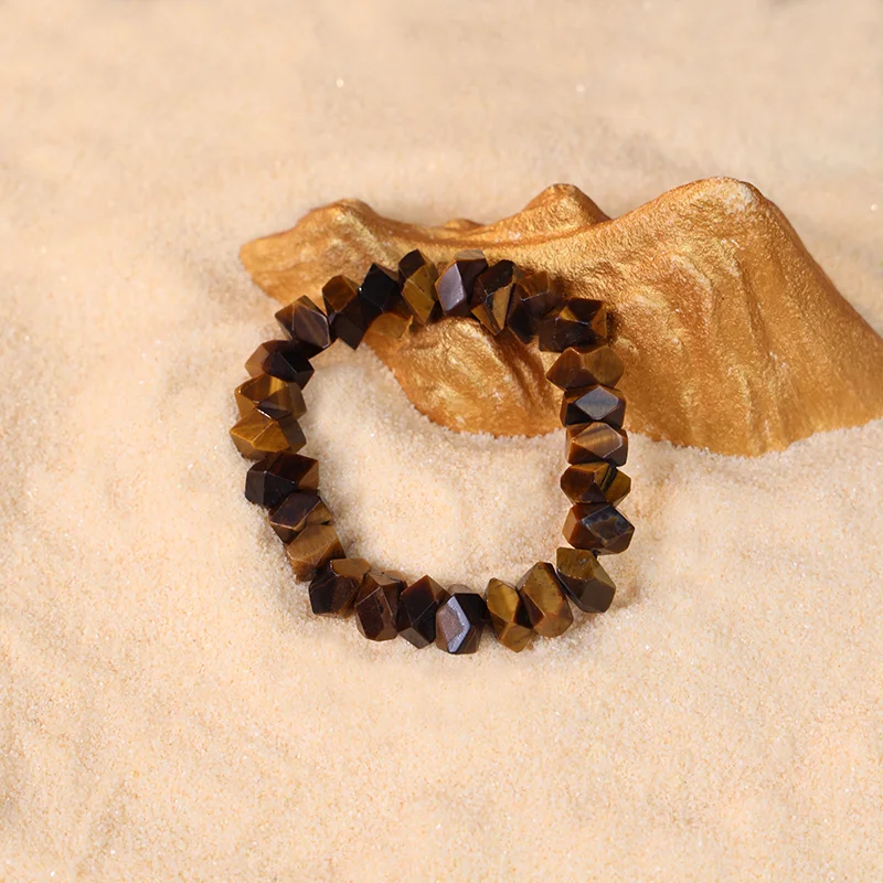 Courage and confidence bracelet with faceted tiger eye beads on sand.