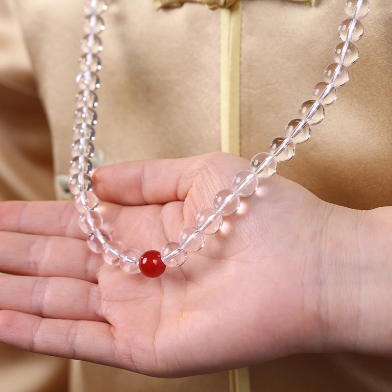Hand gently holding a crystal necklace for meditation and focus.