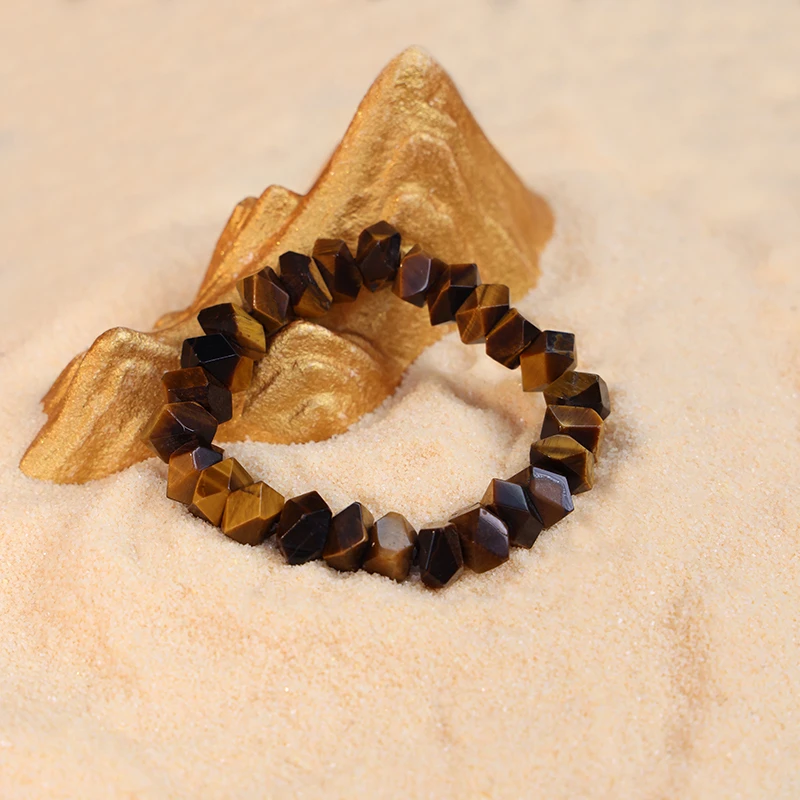 Natural tiger eye bracelet representing strength and vision on sand.