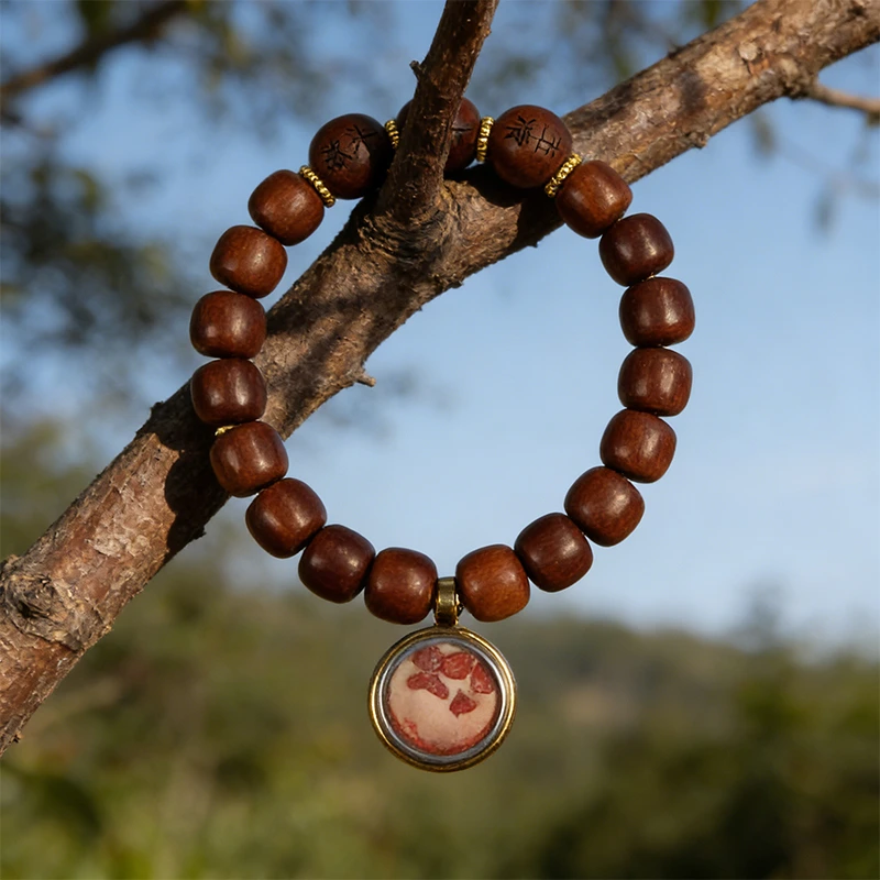 Natural wood element bracelet hanging on a tree branch.