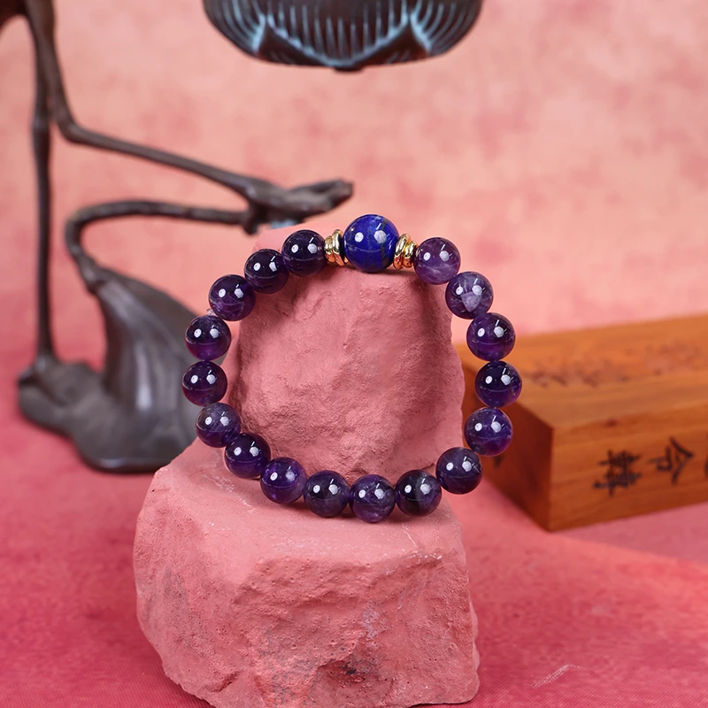 Wisdom and truth bracelet with amethyst beads on dark traditional stand.