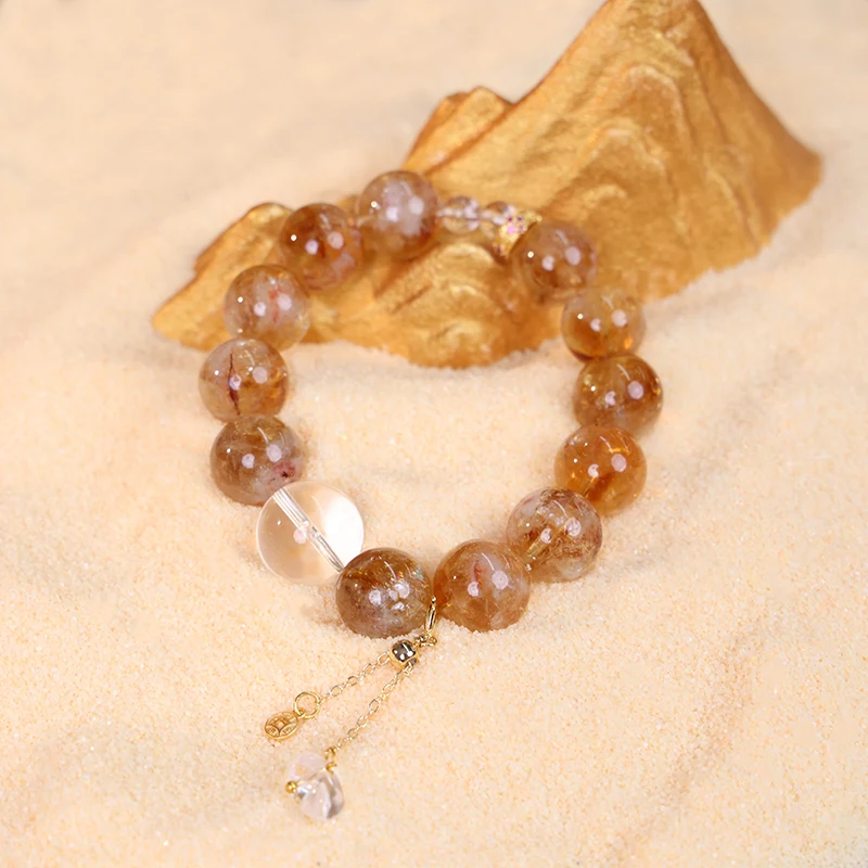 Yellow crystal bracelet featuring a good luck charm on sandy background.